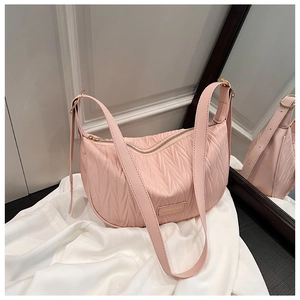 Detail of light pink pleated hobo bag with gold metal plaque on white silk background