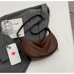 Flat lay of dark brown hobo bag on a grey blazer with minimalist fashion accessories