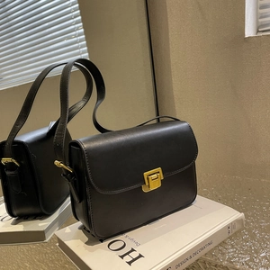 Sac à bandoulière moderne en cuir PU noir avec fermoir doré sur livre décoratif