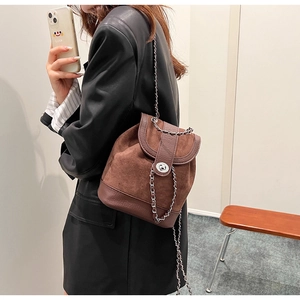 Detailed view of brown suede mini backpack with silver chain strap and metal turn-lock closure