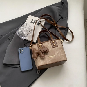 Retro canvas and brown leather mini tote bag with puppy charm on a grey blazer