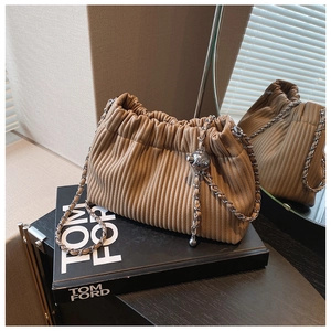 Detail of pleated cloud bucket bag featuring silver chain and spherical metal buckle