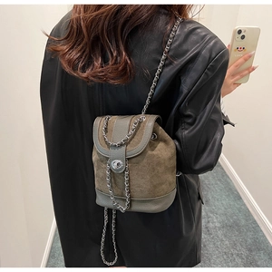 Close-up of olive green suede bucket backpack with silver twist-lock and chain strap