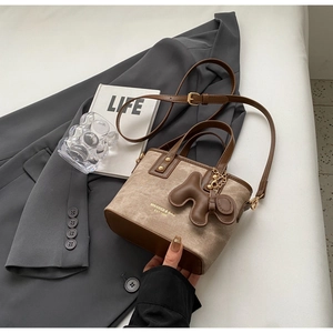 Detail of vintage mini tote bag with leather straps and decorative dog pendant