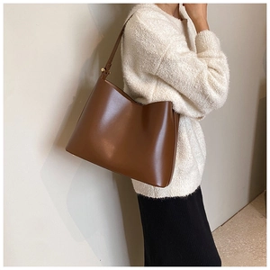 Detail view of smooth dark brown leather bucket bag with gold metal adjustment buckle