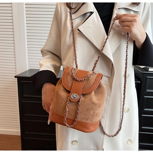 Close-up of brown suede and pebble leather bucket bag with silver chain and twist lock