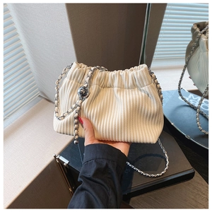 Detail view of beige corduroy bucket bag with pleated texture and silver metal chain strap
