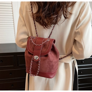 Detail of burgundy leather backpack featuring a silver twist lock and chain shoulder strap