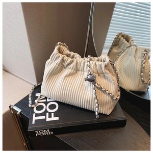 Detail of cream pleated bucket bag with velvet texture and silver chain adjustable ball