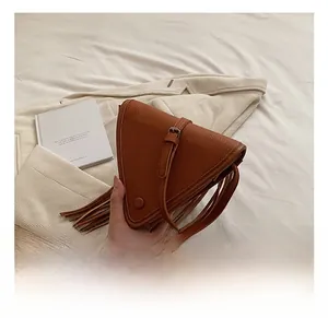 Détail d'un sac triangulaire en cuir marron avec de longues franges et bandoulière