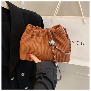 Detail of a brown pleated cloud bag with a silver chain strap and metal ball accessory
