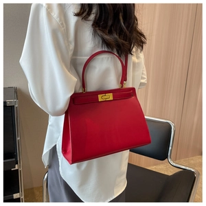 Detail of red leather trapezoid handbag with gold rotating lock and single top handle