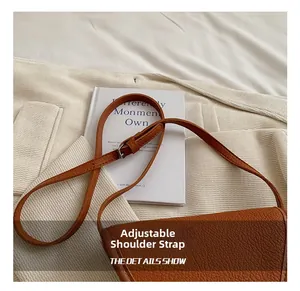 Détail de la bandoulière réglable sur le sac à main marron en cuir grainé litchi