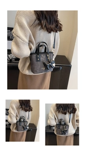 Close-up of a gray marble pattern mini tote bag with a 3D leather dog charm and gold lettering