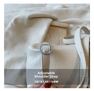 Detail of adjustable leather strap with silver metal buckle on ivory bucket bag