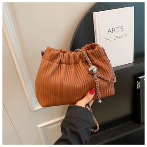 Detail of vertical pleated brown bucket bag with silver chain and sphere metallic ornament