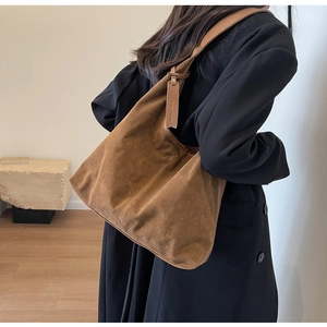 Close-up of retro brown suede tote bag with thick strap and minimalist leather tag detail