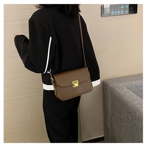 Borsa a tracolla in pelle marrone scuro con fibbia dorata indossata dal modello