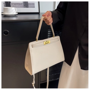 Close-up of cream structured leather handbag with elegant gold metal twist lock buckle