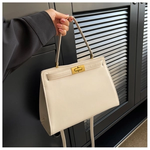 Close-up of cream leather crossbody bag with gold rotating clasp and handle detail