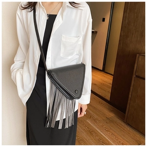 Détail d'un sac bandoulière triangulaire noir avec franges grises sur un mannequin