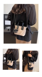 Close-up of beige suede mini tote with black PU handles and animal charm detail