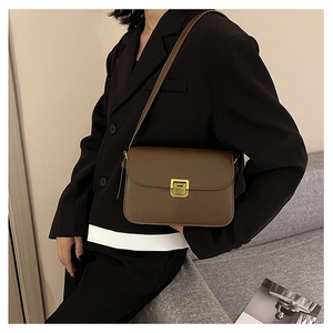 Borsa a tracolla in pelle marrone scuro con fibbia dorata indossata da modella