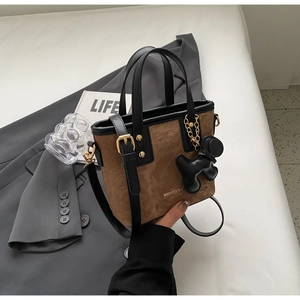 Detail of brown corduroy tote bag with black leather trim and cute puppy charm