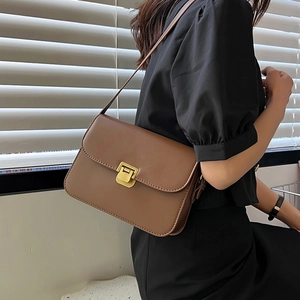 Sac bandoulière rétro en cuir marron café avec fermoir doré porté par un mannequin