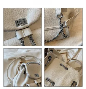 Detail view of white lychee textured backpack with silver chain strap and metal lock