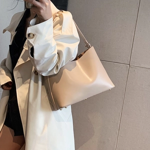Minimalist beige leather shoulder bag with gold metal feet in a mirror selfie view