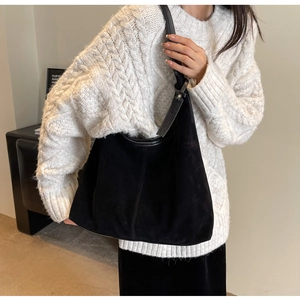 Detailed view of a black suede hobo bag with topstitching and wide shoulder strap