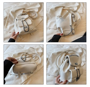 Detail view showing textured white leather backpack with silver chains and multiple pockets