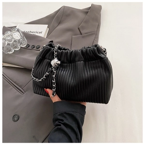 Detail of black pleated bucket bag with silver chain and decorative metal ball charm