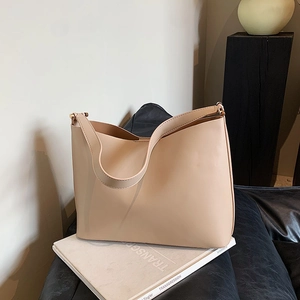 Minimalist apricot leather shoulder bag on an art book with gold metal hardware