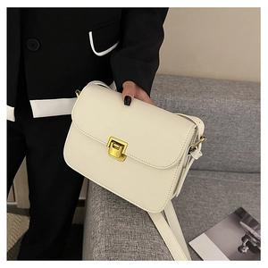 Dettaglio della borsa a tracolla minimalista in pelle crema con elegante chiusura dorata