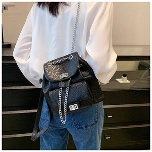 Detail of black pebbled leather backpack with silver turn-lock and chain straps