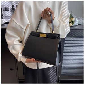 Detail of elegant black trapezoid handbag with gold metal lock and leather texture