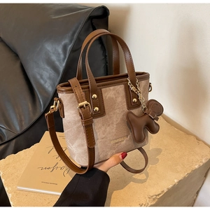 Detail of vintage canvas tote bag with leather trim and cute brown puppy pendant charm