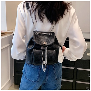 Detail showing the textured black leather backpack with silver chain straps on a model