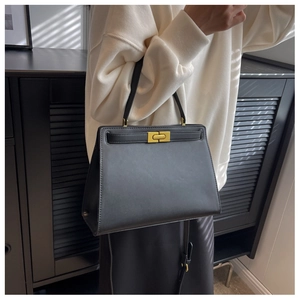 Detail of black structured leather handbag featuring gold twist lock and single handle