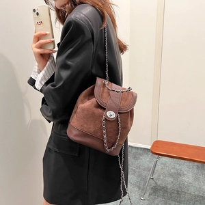Minimalist brown suede and leather backpack for women with silver chain strap worn by model