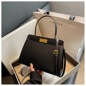 Detail view of structured black leather bag with golden hardware and adjustable strap