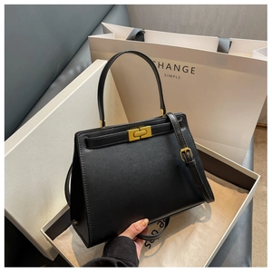 Detail of black faux leather handbag with gold rectangular lock and premium gift packaging