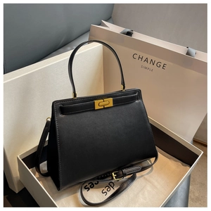 Detail of black leather handbag with gold lock closure in premium gift box packaging