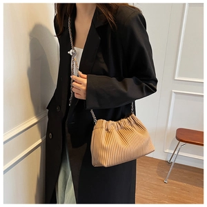 Detail of khaki pleated bucket bag with gold chain strap and metal adjustment ball