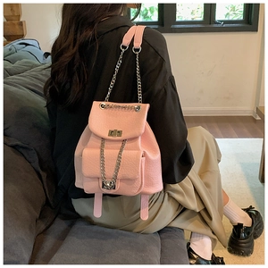 Pink lychee grain leather backpack with chain straps shown on a model in a home setting