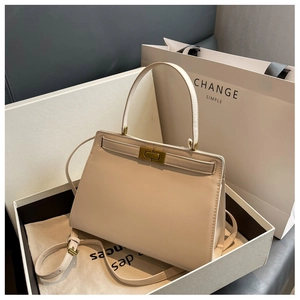 Detailed close-up of a cream trapezoid handbag in a gift box with a metal swivel lock