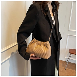 Detail view of brown pleated bucket bag with silver metal chain strap on model