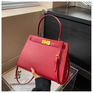 Detail of red leather crossbody bag featuring gold twist lock and fine metallic hardware